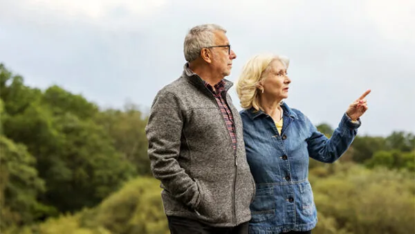 Mature couple walking and enjoying the scenic views surrounded by lush greenery near hotel grounds.